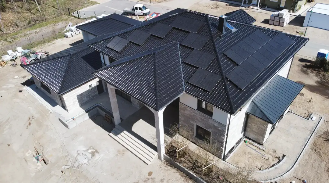 einfamilienhaus-neubau-photovoltaik-dachansicht-kirk-bau-02 Drohnenaufnahme der schwarzen Dachlandschaft eines Wohnhauses mit mehreren Photovoltaikmodulen.