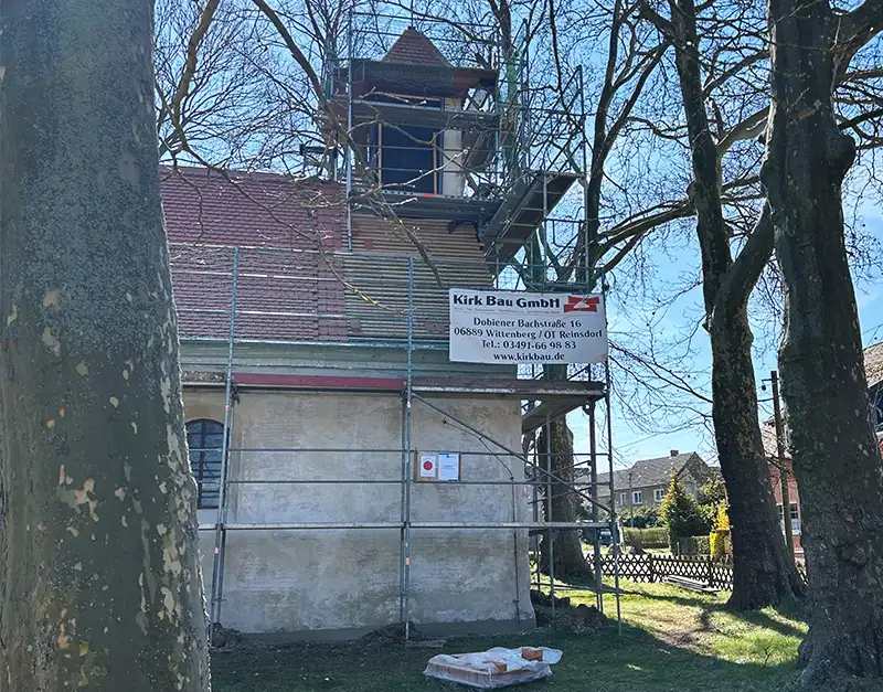 sanierung-gebaeudeturm-baustelle-kirk-bau-01 Historischer Gebäudeturm mit Gerüst und Baustellenbanner der Kirk Bau GmbH.